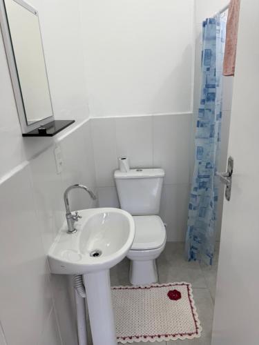 een badkamer met een wastafel, een toilet en een spiegel bij Casa nova bem aconchegante e tranquila in Biguaçu
