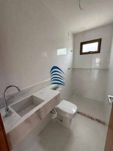 een witte badkamer met een wastafel en een toilet bij Casa in Lauro de Freitas