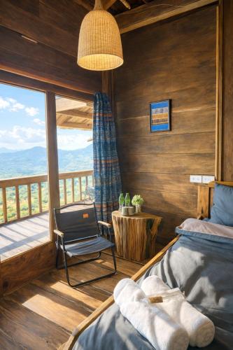 a bedroom with a bed and a chair and a balcony at Nơi Ấy Homestay in Bắc Yên