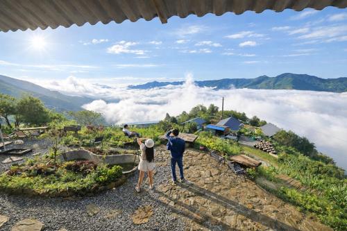 Twee mensen staan bovenop een berg en kijken naar de wolken. bij Nơi Ấy Homestay in Bắc Yên