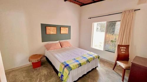 een slaapkamer met een bed, een stoel en een raam bij CALABAZO Casa MonoCai in Santa Marta