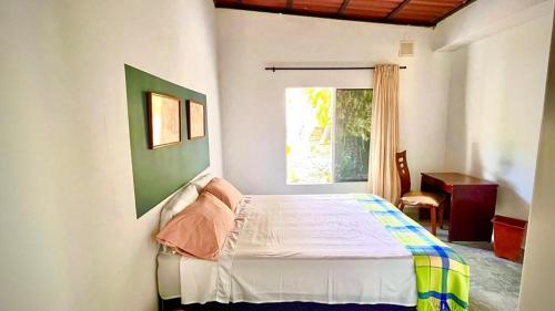 een slaapkamer met een bed in een kamer met een raam bij CALABAZO Casa MonoCai in Santa Marta