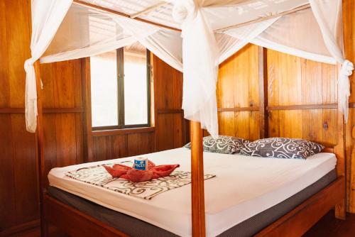 ein Schlafzimmer mit einem Himmelbett und zwei roten Schuhen in der Unterkunft Harmony Bay Resort and Dive Center in Wakai