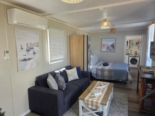 een woonkamer met een bank en een bed bij Sunrise on the Tamar in Deviot