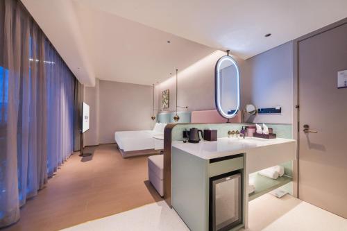 a bathroom with a sink and a bed in a room at Mercure Xishuangbanna in Jinghong