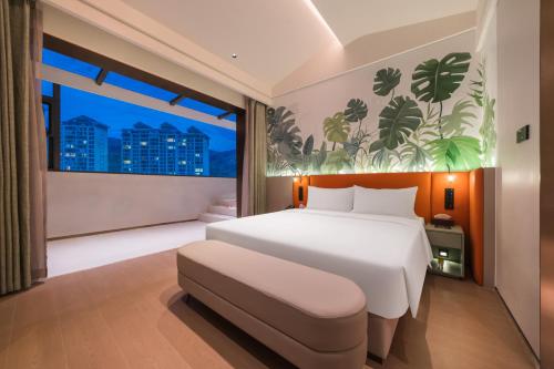 a bedroom with a white bed and a large window at Mercure Xishuangbanna in Jinghong