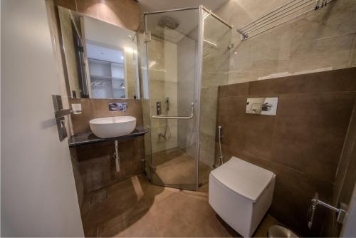 a bathroom with a shower and a toilet and a sink at La Bela Casa Suites, Candolim in Candolim