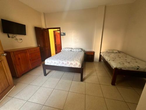 a bedroom with two beds and a tv on the wall at Hostal Luxury Place in Bahía de Caráquez