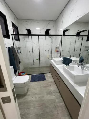 a bathroom with two sinks and a toilet and a shower at Casa de Luxo temporada in Paulínia