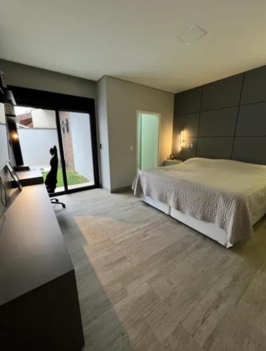 a bedroom with a large bed and a large window at Casa de Luxo temporada in Paulínia
