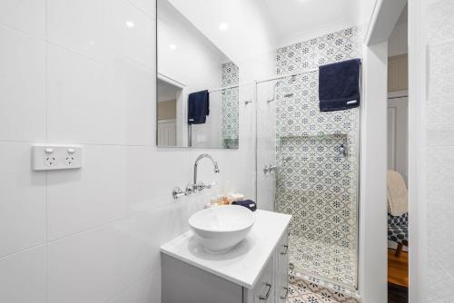 a white bathroom with a sink and a shower at Clark Cottage in Toowoomba