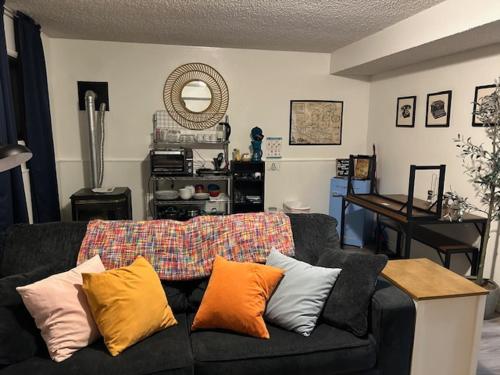 a living room with a black couch with colorful pillows at Cozy East County Jewel in Portland