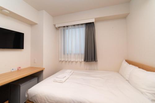 ein Hotelzimmer mit einem Bett und einem Fenster in der Unterkunft Hopetree 天王寺 in Osaka