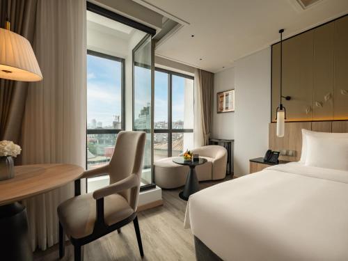 een hotelkamer met een bed, een bureau en een stoel bij HOTEL du LAC SIGNATURE in Hanoi
