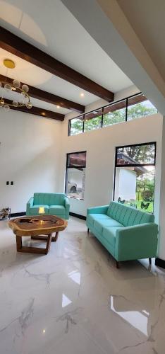 a living room with two green couches and a table at Residential Finca Celeste in Bijagua