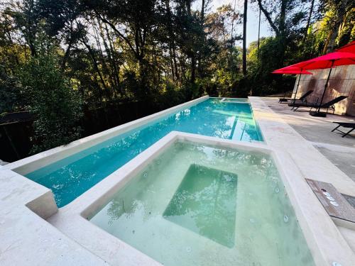 een zwembad in een achtertuin met een rode parasol bij Encino House Hotel Boutique in Valle de Bravo