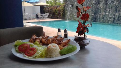 a plate of food on a table next to a pool at Rio Vista Inn Business High Class Hotel Poza Rica in Poza Rica de Hidalgo