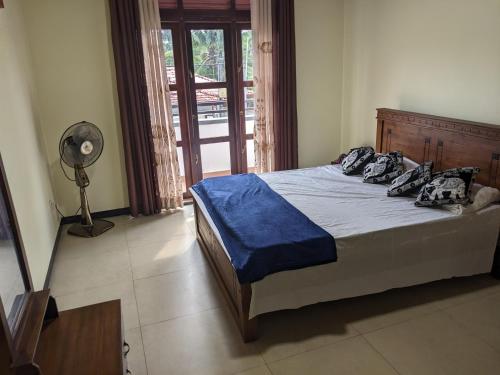 a bedroom with a bed with blue sheets and a fan at SR Home stay in Matugama