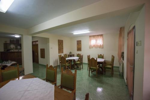 a dining room with tables and chairs and a kitchen at Béluci Panzió in Odorheiu Secuiesc