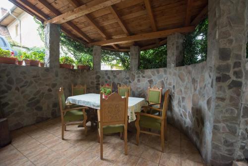 a table and chairs on a patio with a stone wall at Béluci Panzió in Odorheiu Secuiesc