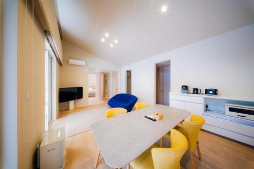 ein Wohnzimmer mit einem Tisch und gelben Stühlen in der Unterkunft Mimi Hakuba by Jade Villa in Hakuba