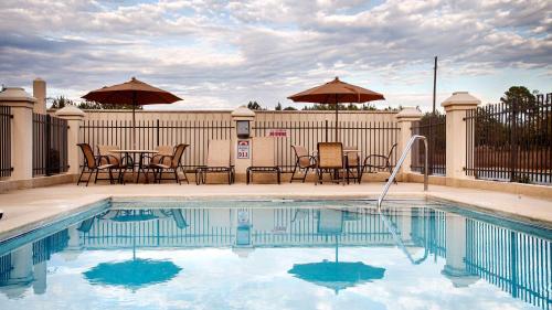 a swimming pool with chairs and tables and umbrellas at Country Inn & Suites by Radisson, Midway - Tallahassee West in Midway