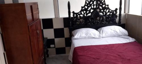 een slaapkamer met een bed met een zwart hoofdeinde en witte kussens bij casa de hospedaje urcunina in Pasto