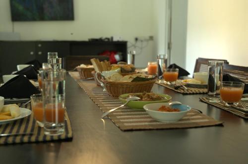 een lange tafel met borden eten en drinken bij Rain Drops Wellness Villa Sinharaja in Mederipitiya