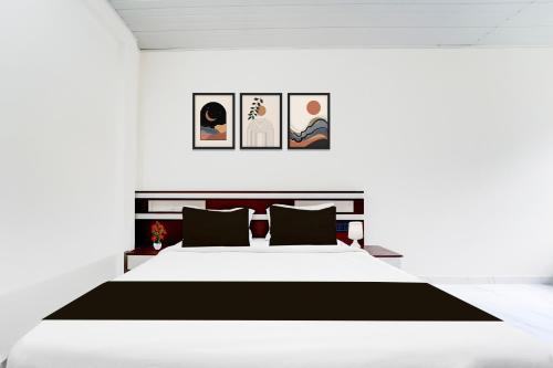 a bedroom with a white bed and pictures on the wall at Super Hotel O North Kalamassery in Cochin