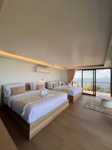zwei Betten in einem Zimmer mit großen Fenstern in der Unterkunft La Villa Hill-ลาวิลล่าฮิลล์ in Mon Jam