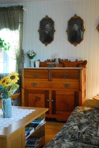 a bedroom with a wooden dresser with a picture on the wall at Maison de campagne le Nichouette in Les Éboulements