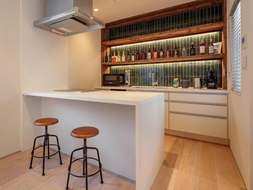 a kitchen with a bar with two stools at 材木座海水浴場まで徒歩3分 - Shell The Third-鎌倉で楽しむカリフォルニアスタイルの上質な空間 in Kamakura