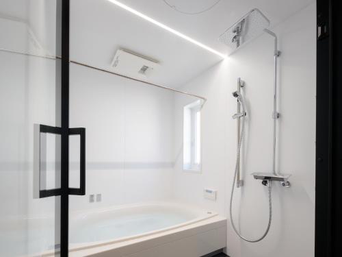 a white bathroom with a shower with a mirror at 材木座海水浴場まで徒歩3分 - Shell The Third-鎌倉で楽しむカリフォルニアスタイルの上質な空間 in Kamakura