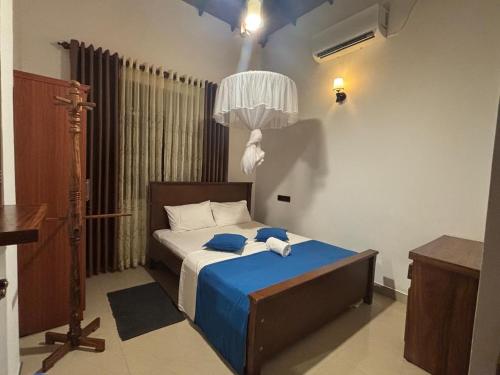 une chambre avec un lit avec une couverture bleue dans l'établissement Punida villa, à Mirissa