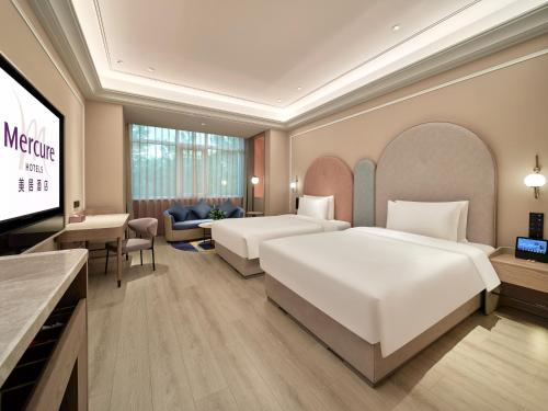 a hotel room with two beds and a flat screen tv at Mercure Beijing Universal Resort in Beijing