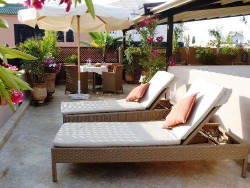 eine Terrasse mit 2 Liegestühlen und einem Sonnenschirm in der Unterkunft Riad Viva in Marrakesch
