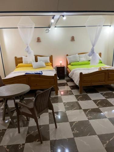 a bedroom with two beds and a table and chair at Das Haus am Meer in Safaga
