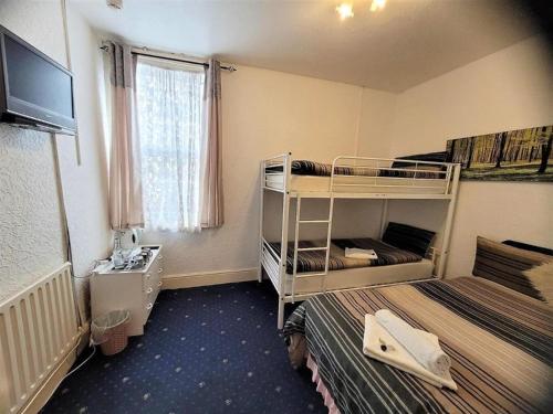 a small room with two bunk beds and a television at Holiday Plus - 50 Palatine Road in Blackpool