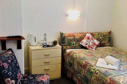 a bedroom with a bed with a dresser and a chair at Holiday Plus - 50 Palatine Road in Blackpool