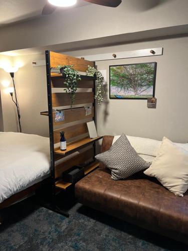 a bedroom with a bed and a couch and a shelf at Tanuki Inn Korien Kyoto Osaka in Neyagawa