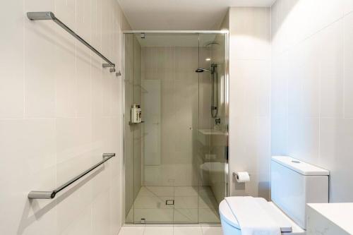 a white bathroom with a shower and a toilet at 1BR Queens Wharf City Charm with Balcony Views - LV 15 in Brisbane
