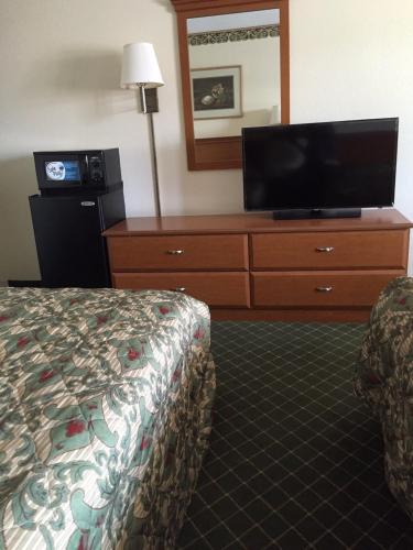 a hotel room with a bed and a flat screen tv at Economy Inn Dillon in Dillon