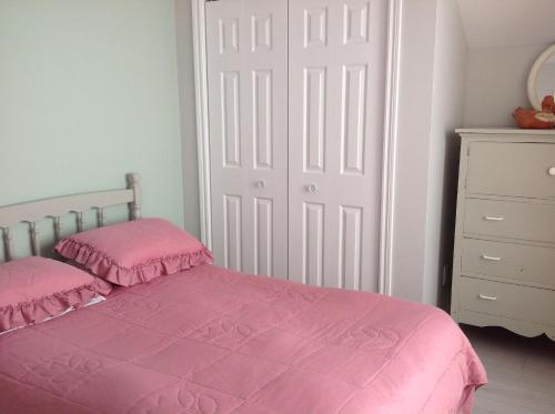 a bedroom with a pink bed and a white door at Domaine sur une plage in Saint-Félicien