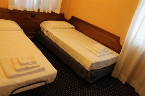 two beds in a hotel room with white towels at Hotel Don Carlo in Broni