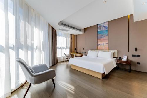 a bedroom with a white bed and a chair at Mercure Huhhot Economic Zone in Hohhot