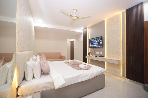 a bedroom with a bed with white sheets and a tv at Hotel Qualia Oak in Hyderabad