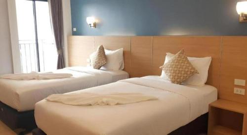 two beds in a hotel room with white sheets at Ceniq Hotel in Sathani Nakhon Lampang
