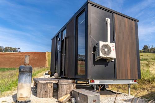a black tiny house sitting on top of logs at Perrys North by Tiny Away in Forth