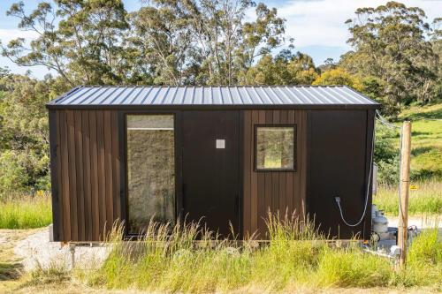 a brown shed with a fire hydrant in a field at Perrys North by Tiny Away in Forth