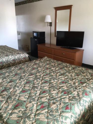 a hotel room with a bed and a flat screen tv at Economy Inn Dillon in Dillon